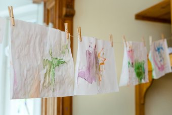 Auf einer Leine hängen mehrere Bilder zum Trocknen. Sie sind mit Wäscheklammern aufgehangen.